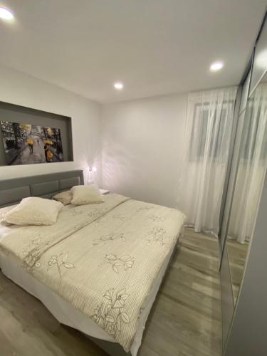 ein Schlafzimmer mit einem großen Bett mit weißer Bettwäsche in der Unterkunft Apartment Bono in Baška Voda