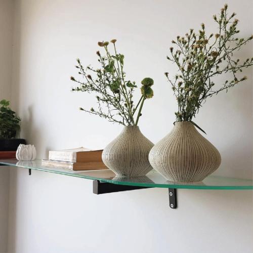 two vases sitting on a glass shelf with flowers at Nu Fifty Two in Amman
