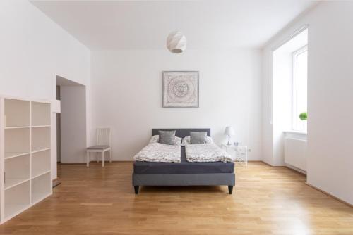 una camera bianca con letto e pavimento in legno di Charming Flat & Balcony near CentralStation Apt 5 a Vienna