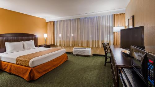 a hotel room with a bed and a flat screen tv at Airport Honolulu Hotel, Trademark Collection by Wyndham in Honolulu