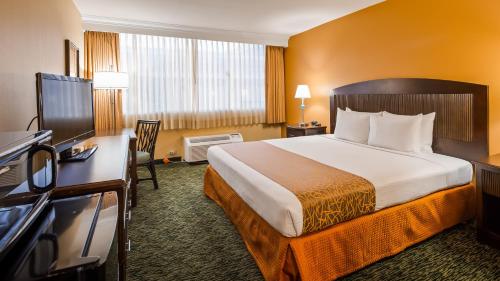 a hotel room with a bed and a flat screen tv at Airport Honolulu Hotel, Trademark Collection by Wyndham in Honolulu