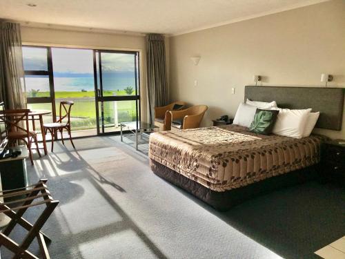 ネイピアにあるHarbour View Seaside Accommodation Napierのベッドとバルコニー付きのホテルルーム