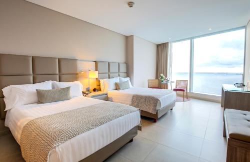 a hotel room with two beds and a large window at Estelar Cartagena de Indias Hotel y Centro de Convenciones in Cartagena de Indias