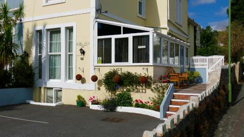 a yellow house with a porch with flowers on it at Marmalade Bed & Breakfast in Torquay