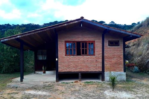 a small brick house with a red window at Pousada Chales Joao de Barro in Visconde De Maua