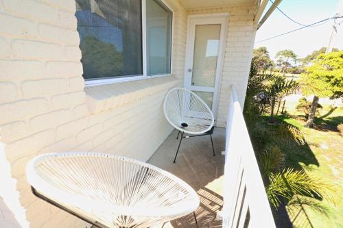 a white chair and a table on a porch at Beachcomber - Pet Friendly in Merimbula