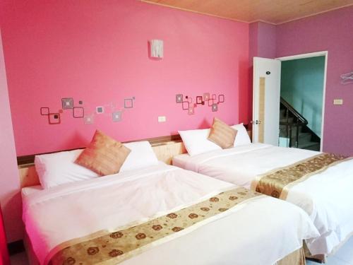 two beds in a room with pink walls at 別野山莊民宿 in Baisha