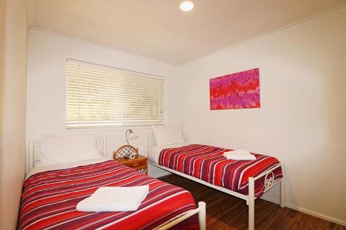 a bedroom with two beds and a window with a painting at Beachcomber - Pet Friendly in Merimbula