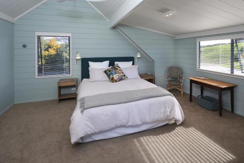 a bedroom with a bed and a desk and two windows at Noll View in Oneroa