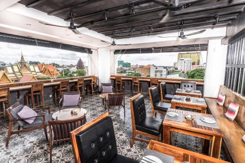 a restaurant with tables and chairs and large windows at PATIO Hotel & Urban Resort in Phnom Penh