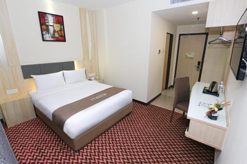 a hotel room with a large bed and a table at Metro Hotel Bukit Bintang in Kuala Lumpur