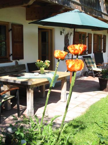 a table with an umbrella and a table with flowers at Landhaus Am Arzbach in Bad Tölz