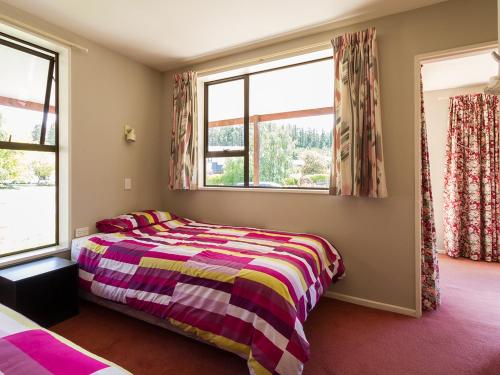 Un dormitorio con una cama y dos ventanas. en Mill House - Wanaka Holiday Home, en Wanaka