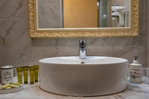 a white sink in a bathroom under a mirror at Byzantio Hotel & Apartments in Parga