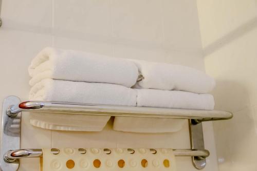 a stack of towels on a towel rack in a bathroom at Hotel Rainbow in Cameron Highlands
