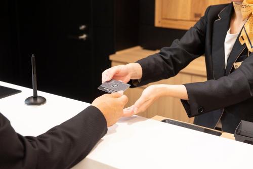 a man handing a woman a remote control at a table at Wires Hotel Shinagawa Seaside in Tokyo