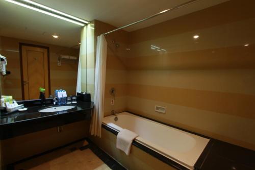 Swiss-Belhotel Maleosan Manado في مانادو: حمام مع حوض ومغسلة ومرآة