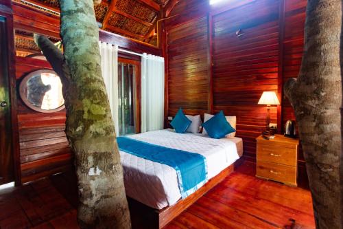 a bedroom with a bed next to a tree at Caesar Phu Quoc Hotel in Phu Quoc