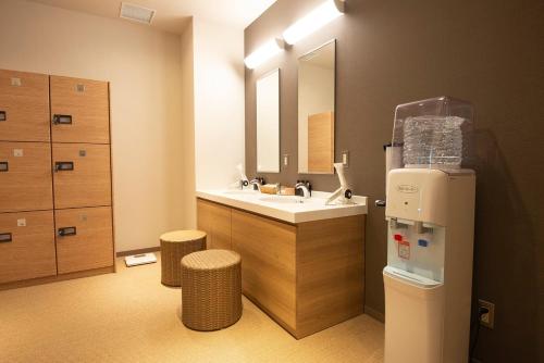 a bathroom with a sink and a mirror and a refrigerator at Wires Hotel Shinagawa Seaside in Tokyo