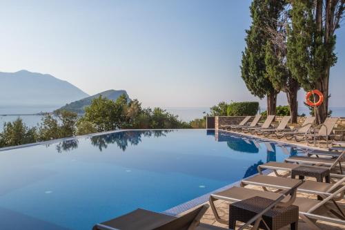 a beach with a pool and a balcony overlooking the ocean at Avala Resort & Villas in Budva
