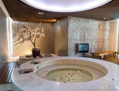 Zimmer mit einer großen Badewanne mit Vase und einem TV in der Unterkunft All-Ur Boutique Motel - Taichung Branch in Taichung