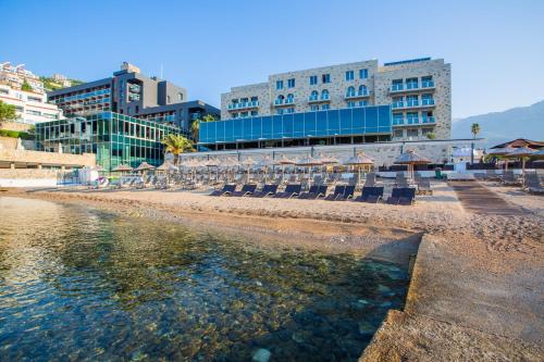 a group of chairs on a beach with buildings at Avala Resort & Villas in Budva