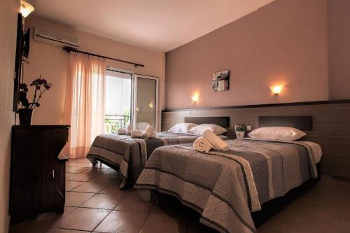 two beds in a hotel room with a window at GOLDEN SUN STUDIOS in Kallithea Halkidikis