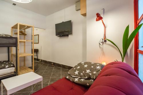 Una sala de estar con un sofá rojo y un televisor de pantalla plana. en Apartma N'Poznam, en Liubliana