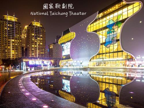 a building with a reflection in the water at night at Backpacker 41 Hostel - Taichung in Taichung