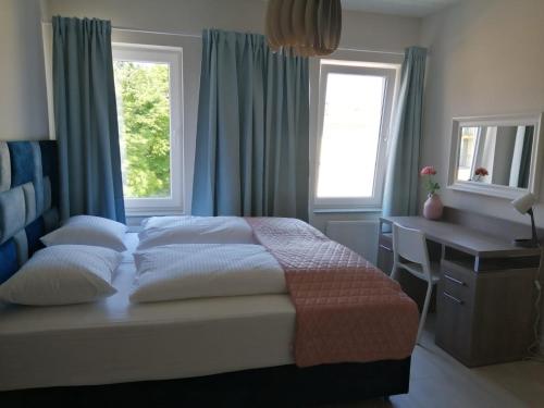 a bedroom with a bed and a desk and windows at APARTAMENTY POSEJDON in Świnoujście