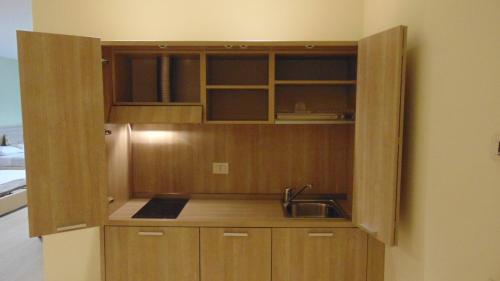 a kitchen with a sink and wooden cabinets at Turin Airport Hotel & Residence in San Francesco al Campo