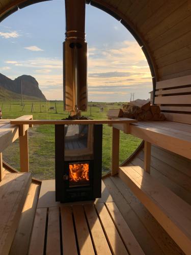 a wood stove in a cabin with a view of a field at Unstad Arctic Resort in Unstad
