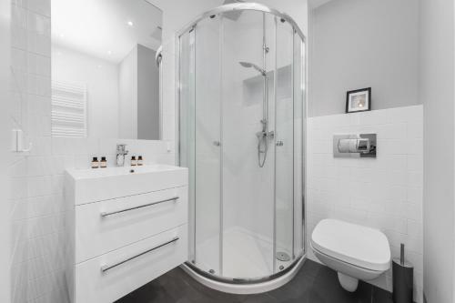 a white bathroom with a shower and a toilet at Symphony Baltica Towers Apartamenty in Gdańsk