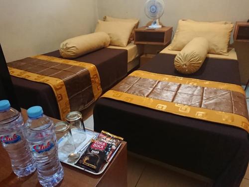 a room with two beds and water bottles on a table at Villagio Hotel in Pameungpeuk