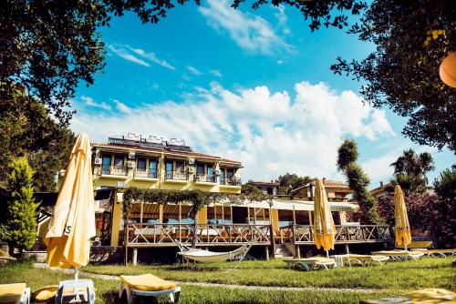 un hôtel avec des chaises et des parasols devant lui dans l'établissement Limonata Hotel Assos, à Assos