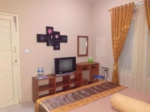 a bedroom with a bed and a tv in a room at Villagio Hotel in Pameungpeuk