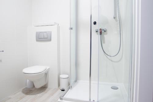 a white bathroom with a shower and a toilet at AL-DOM apartamenty Grey 112 Olymp in Kołobrzeg