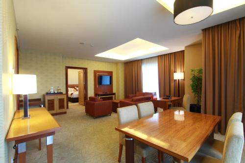 une chambre d'hôtel avec une table et un salon dans l'établissement Swiss-Belhotel Maleosan Manado, à Manado