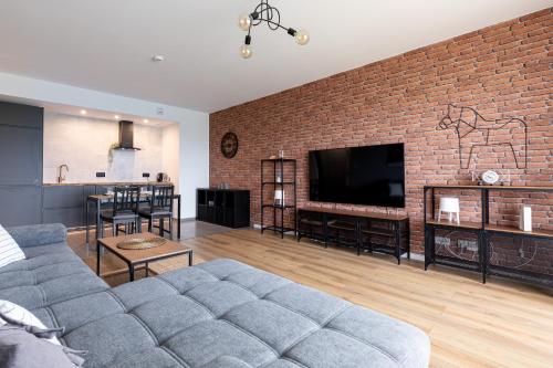 a living room with a couch and a brick wall at Symphony Baltica Towers Aparthotel in Gdańsk