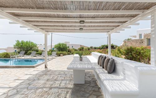 a white bench under a pergola next to a pool at Mykonos Unique Villas in Kalafatis