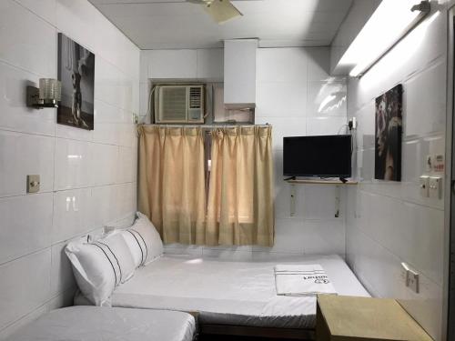 Habitación pequeña con cama y TV. en HK International Hostel, en Hong Kong