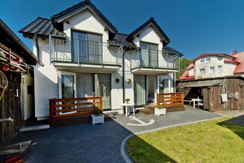 a white house with a patio and a yard at Apartamenty In Chałupy Kaperska in Chałupy