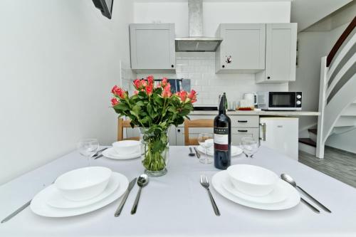 a white table with white plates and a bottle of wine at Apartamenty In Chałupy Kaperska in Chałupy