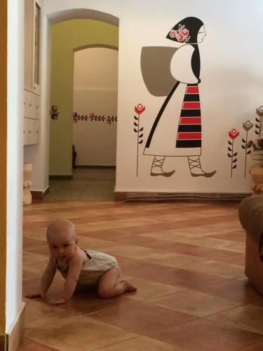 a baby sitting on the floor in a room with a woman on the wall at Retro Hostel in Cluj-Napoca