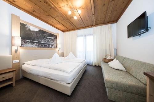 um quarto de hotel com uma cama e um sofá em Hotel Alpenhof em Ultimo