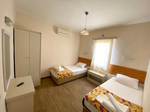 a small room with two beds and a window at Maison 48 Apart Hotel in Gümbet
