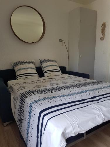 ein Schlafzimmer mit einem großen Bett und einem Spiegel an der Wand in der Unterkunft Océane Studio in Paimpol