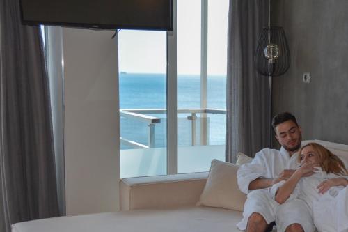 a man and woman sitting on a bed in a hotel room at Scorpios Sea Side Hotel in Piraeus