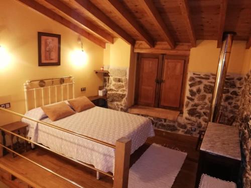 1 dormitorio con 1 cama en una habitación con techos de madera en Apartamentos Rurales A Torre en Porquera