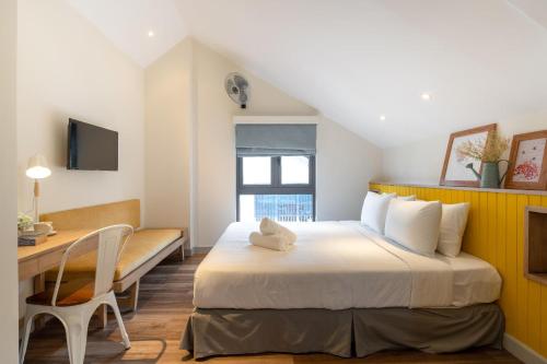 a hotel room with a bed and a desk and a tv at La Em Boutique Villa in Da Lat